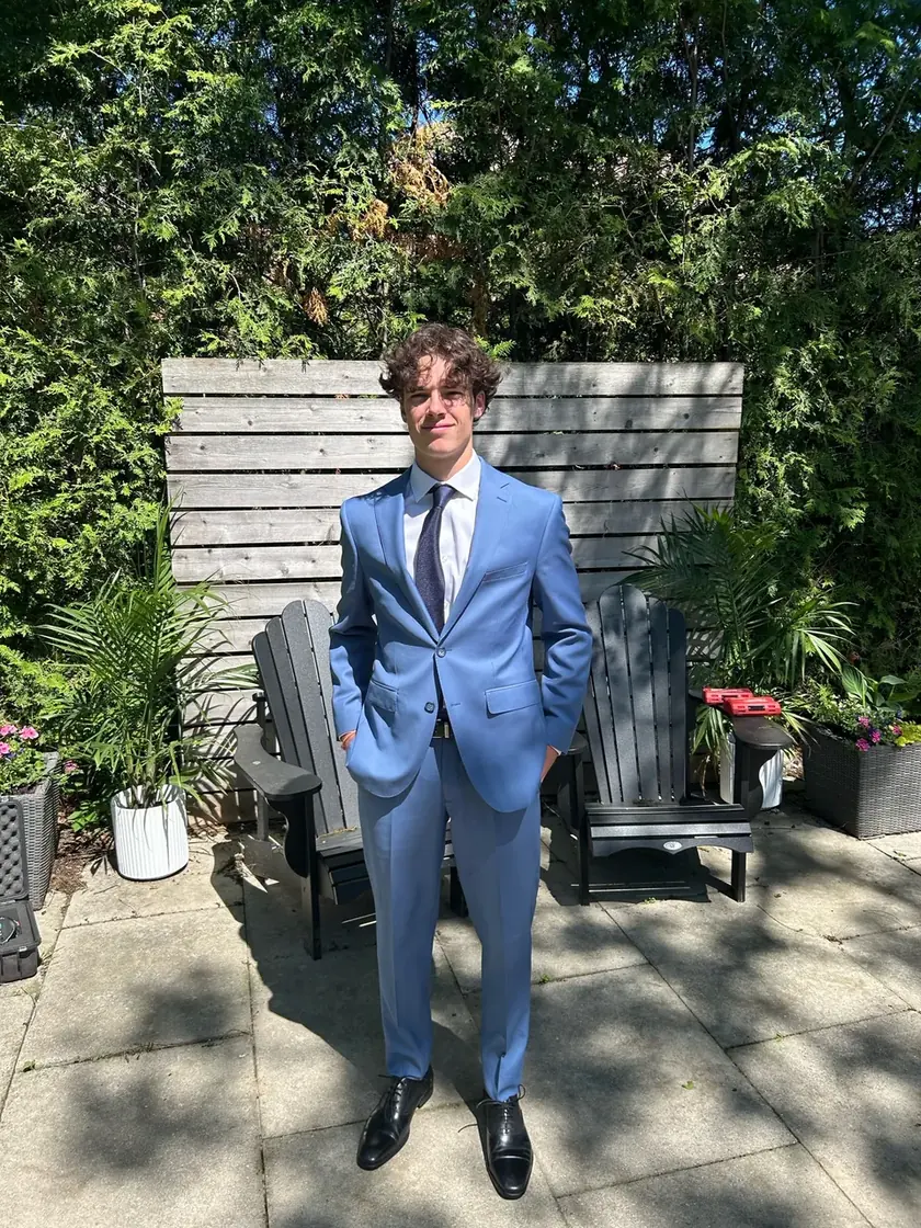 Jack Reeves in a light blue suit, standing in a garden